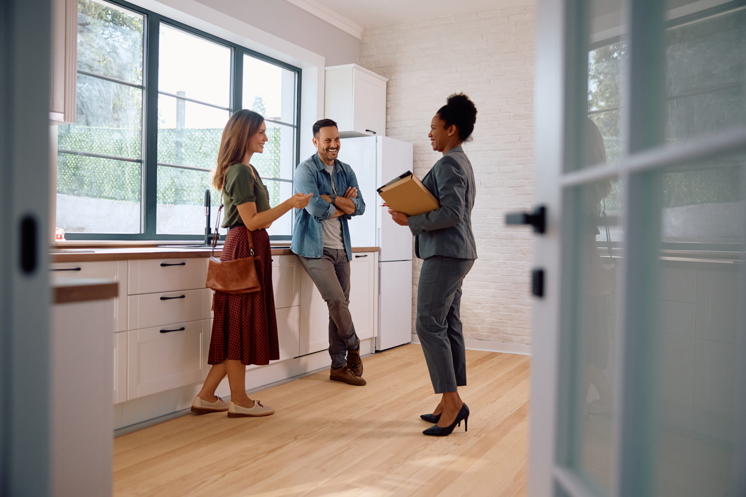 Happy couple talking with real estate agent while buying new home.